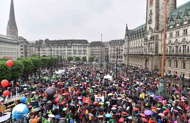 participants hold placards during a demonstration in front of the hamburg city hall rathaus called by several ngos ahead of the g20 summit in hamburg on a rainy july 2 2017 photo afp