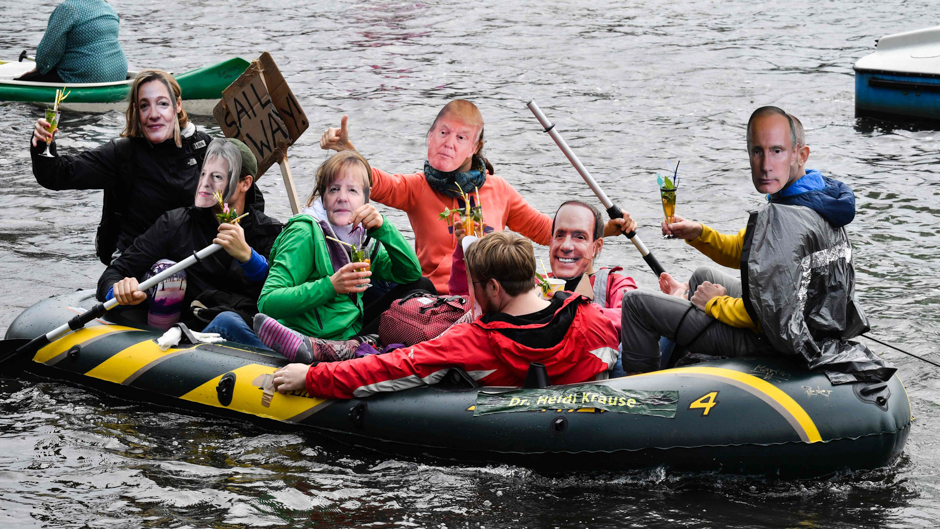 protestors with masks of politicians drink cocktails in a boat on the alster river during a demonstration called by several ngos ahead of the g20 summit in hamburg photo afp