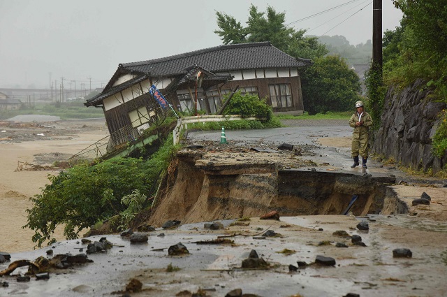 a resident checks a collapsed road side near a damaged house following heavy flooding in asakura fukuoka prefecture on july 7 2017 huge floods engulfing parts of southern japan are reported to have killed at least six people and left hundreds stranded as the torrents swept away roads and houses and destroyed schools photo afp