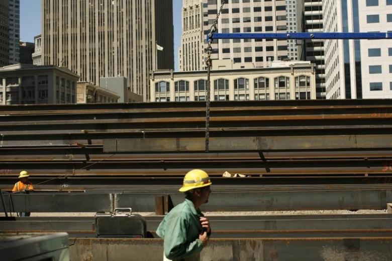 workers guide steel beams into place at a construction site photo reuters