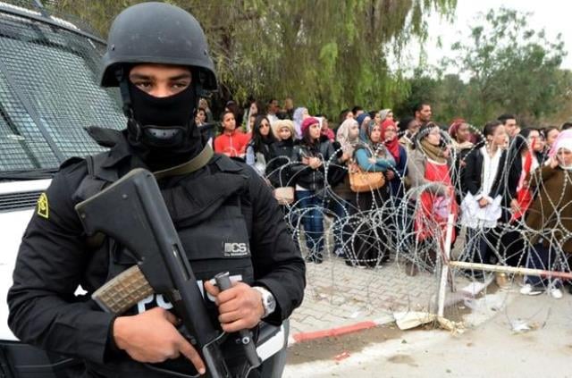 a policeman stands guard as tunisian demonstrators shout slogans and hold placards during a protest outside tunisia 039 s bardo national museum on march 24 2015 in tunis condemning the attack on the tourist site six days earlier which killed 21 people photo afp