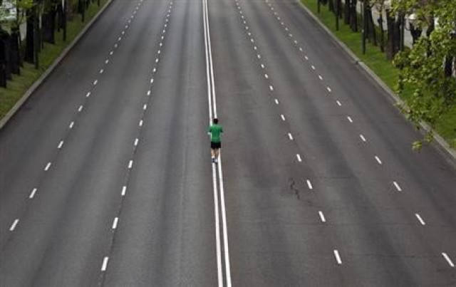 a runner warms up in the middle of an empty avenue photo reuters a runner warms up in the middle of an empty avenue photo reuters