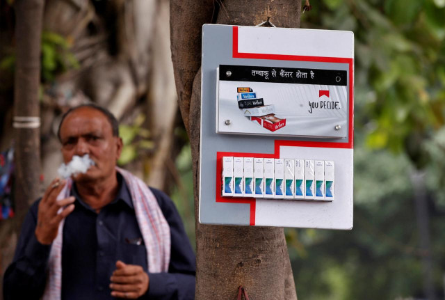 a man smokes next to a cigarette advertisement hung on a tree at a marketplace in new delhi india may 3 2017 photo reuters a man smokes next to a cigarette advertisement hung on a tree at a marketplace in new delhi india may 3 2017 photo reuters