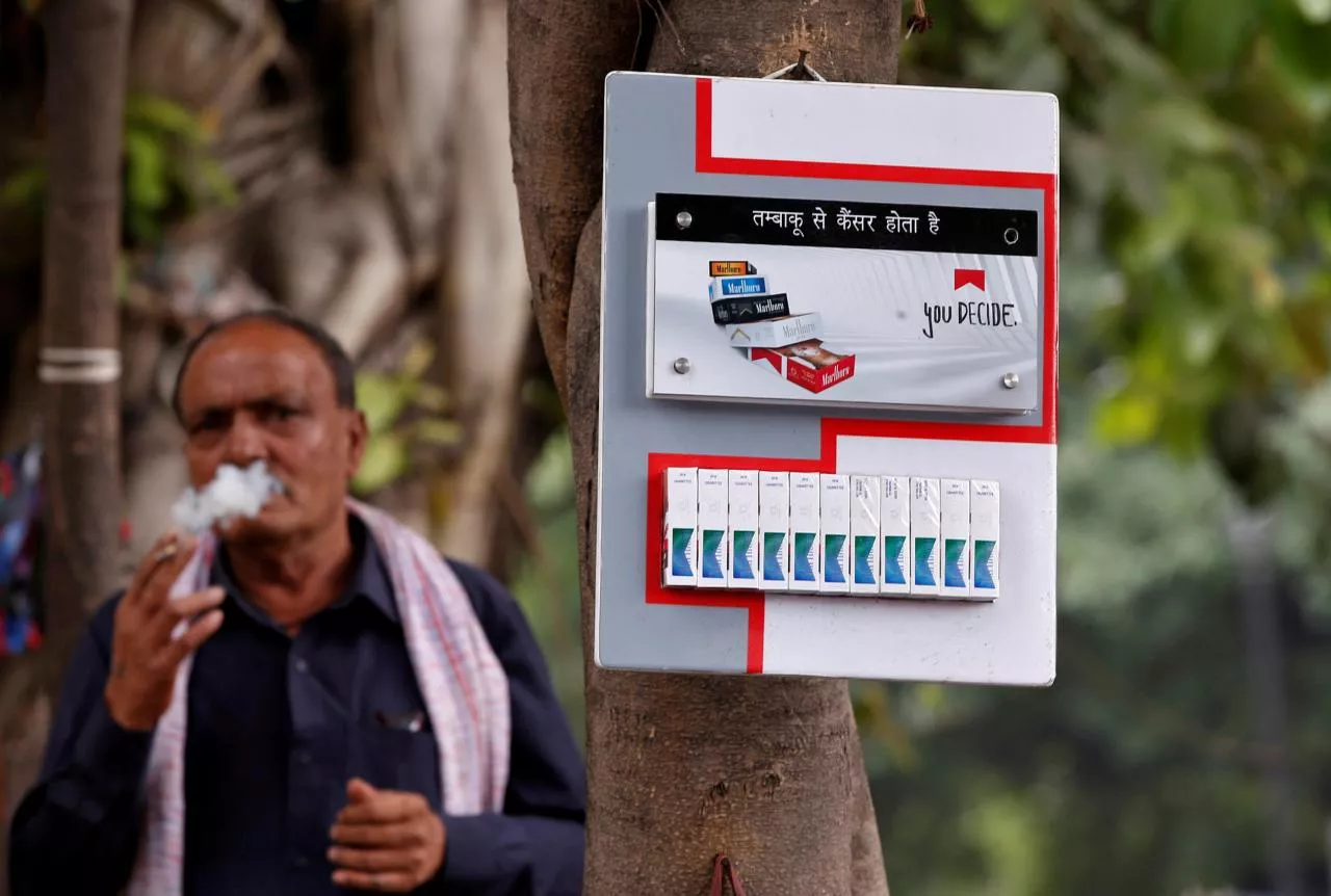 a man smokes next to a cigarette advertisement hung on a tree at a marketplace in new delhi india may 3 2017 photo reuters a man smokes next to a cigarette advertisement hung on a tree at a marketplace in new delhi india may 3 2017 photo reuters