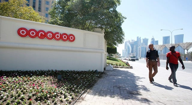 men look at the logo of qatar telecom ooredoo formerly qatar telecom qtel as they walk past the company 039 s head office in doha march 16 2013 photo reuters