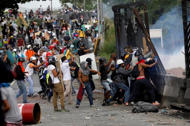 demonstrators clash with riot security forces at the fence of an air base while rallying against venezuela 039 s president nicolas maduro in caracas venezuela photo reuters