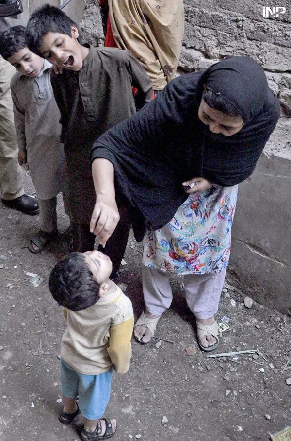 a polio worker administers polio vaccine to a child in the ongoing anti polio campaign photo inp a polio worker administers polio vaccine to a child in the ongoing anti polio campaign photo inp
