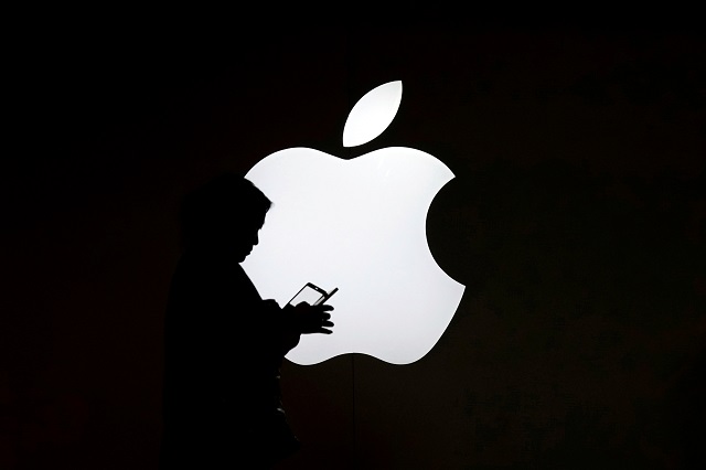 a woman looks at the screen of her mobile phone in front of an apple logo outside its store in shanghai china photo reuters