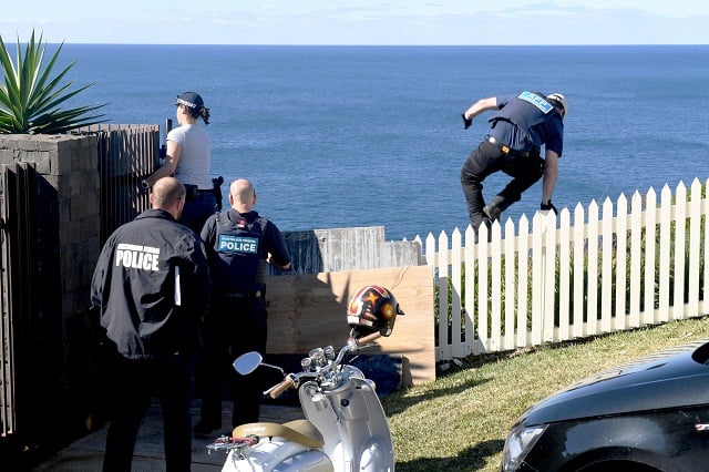 a policeman jumps a fence at the home of john ibrahim during a police operation in sydney australia august 8 2017 photo reuters