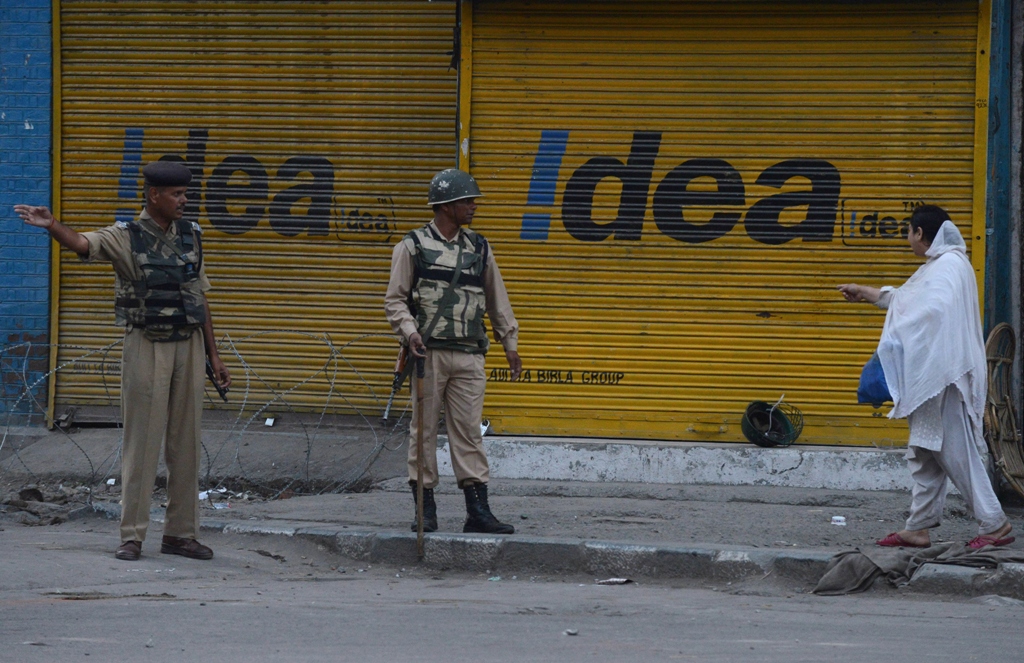 an indian paramilitary troop stops a kashmiri woman during a curfew imposed in srinagar on july 19 2013 photo afp