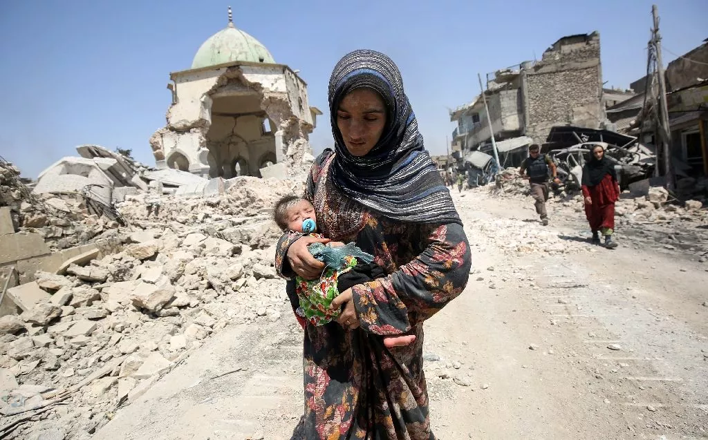 an iraqi woman carrying a child walks by the destroyed al nuri mosque as she flees the old city of mosul photo afp an iraqi woman carrying a child walks by the destroyed al nuri mosque as she flees the old city of mosul photo afp