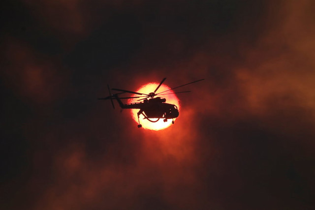 a firefighting helicopter flies in front of the setting sun as a wildfire burns near the village of kapandriti north of athens greece photo reuters
