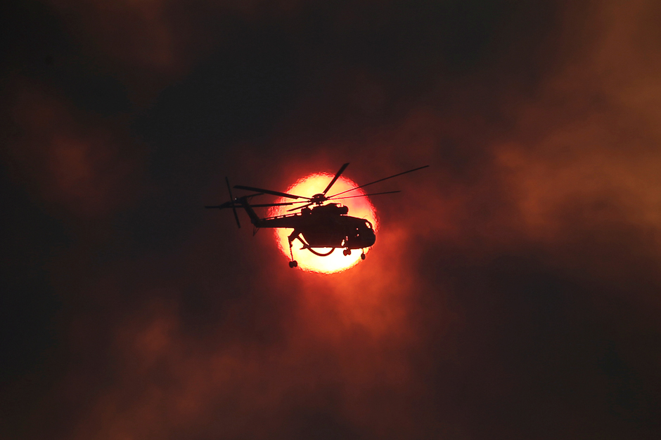 a firefighting helicopter flies in front of the setting sun as a wildfire burns near the village of kapandriti north of athens greece photo reuters