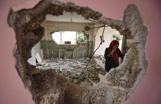 a woman checks the remains of the house of a palestinian man who killed three jewish residents of a nearby israeli settlement after it was demolished by israeli authorities in the west bank village of kobar near ramallah photo afp