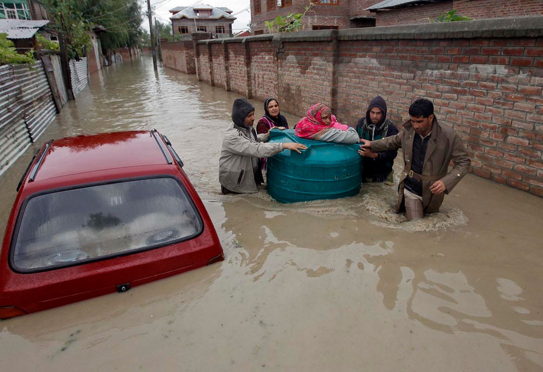 people transport a sick woman in an empty water tank on a flooded street photo reuters