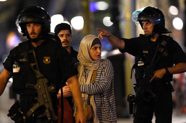 spanish policemen accompany clients of a store outside a cordoned off area after a van ploughed into the crowd killing 13 persons and injuring over 80 on the rambla in barcelona photo afp