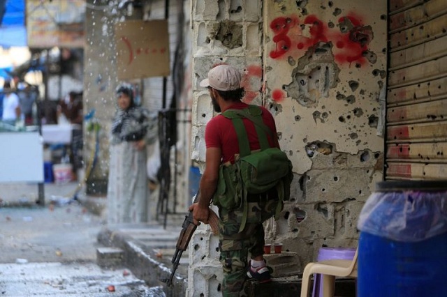 a member of the joint palestinian security force stands in front of a bullet riddled wall inside the ain el hilweh refugee camp photo reuters