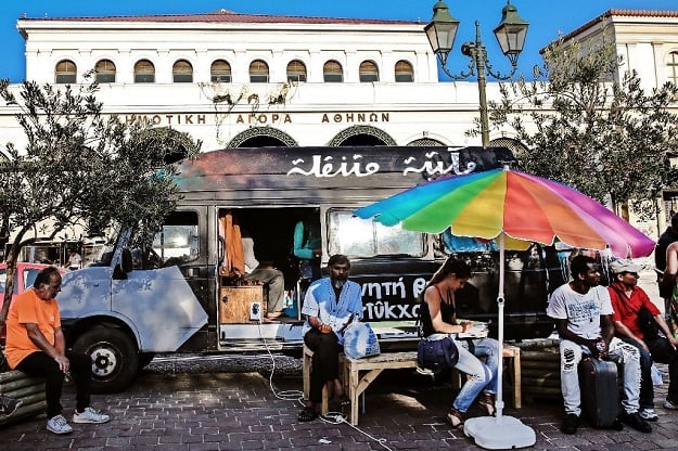 people sit outside a library van in central athens one of the initiatives in greece to offer reading and books to the tens of thousands of refugees stranded in the country photo afp