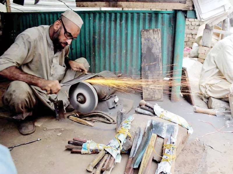 a blacksmith sharpens a meat cleaver at his store photo nni a blacksmith sharpens a meat cleaver at his store photo nni
