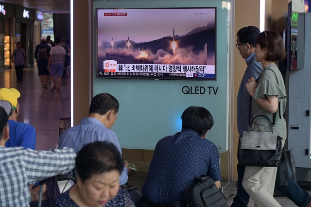 people are seen past a television screen showing file news footage of a north korean missile launch at a railway station in seoul on august 26 2017 north korea fired three short range ballistic missiles on august 26 the us military said following weeks of heightened tensions between washington and pyongyang
