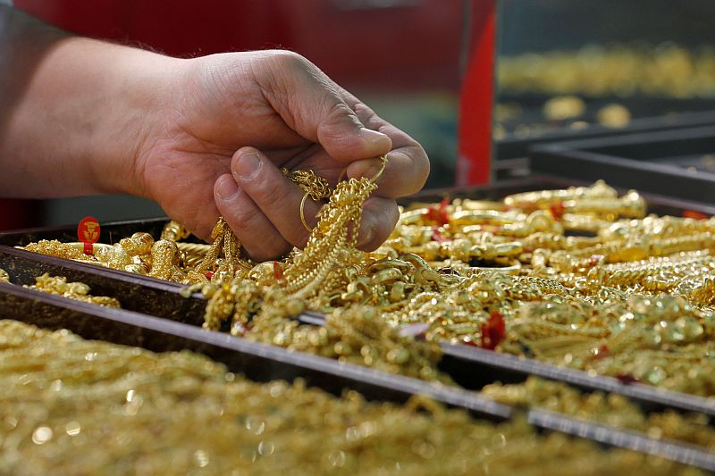 a salesman holds gold to sell to a customer at a gold shop photo reuters