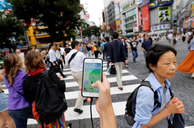 a man plays the augmented reality mobile game quot pokemon go quot by nintendo on his mobile phone as he walks at a busy crossing in shibuya district in tokyo japan july 22 2016 photo reuters