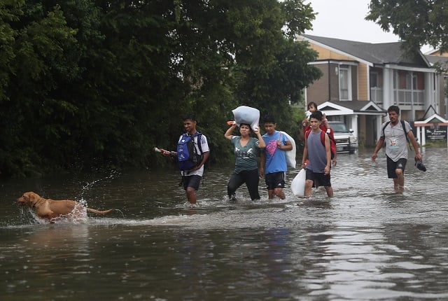 people walk down a flooded street as they evacuate their homes after the area was inundated with flooding from hurricane harvey on august 27 2017 in houston texas harvey which made landfall north of corpus christi late friday evening is expected to dump upwards to 40 inches of rain in texas over the next couple of days photo afp