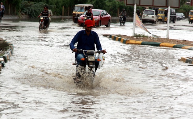 a motorcyclist travels through water on a main thoroughfare of the city many areas were submerged after the rain photo express