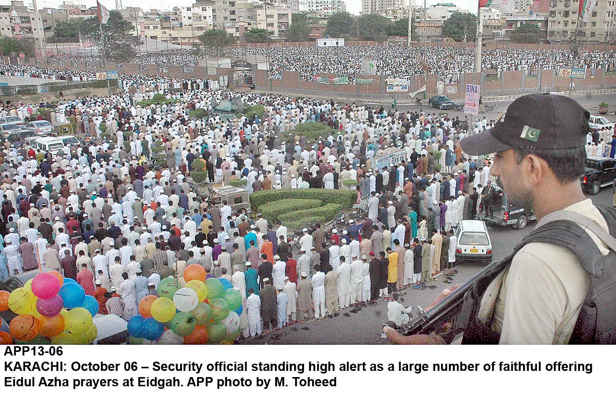 in this file photo a security official stands alert as people offer eidul azha prayers photo app