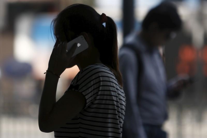 a woman speaks on her iphone as she walks on a busy street in downtown shanghai photo reuters