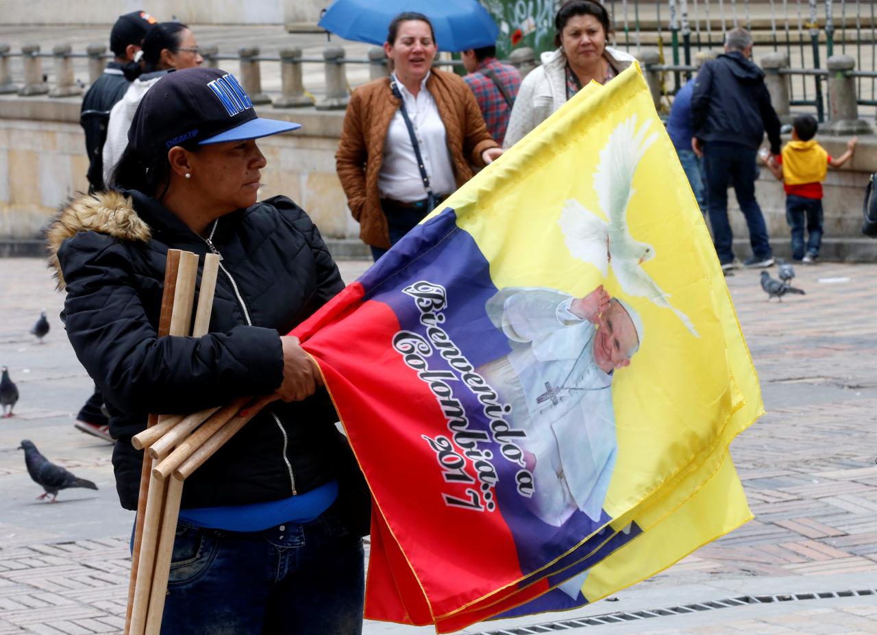 a woman sells flags with the image of pope francis outside the cathedral of bogota in bolivar square colombia photo reuters