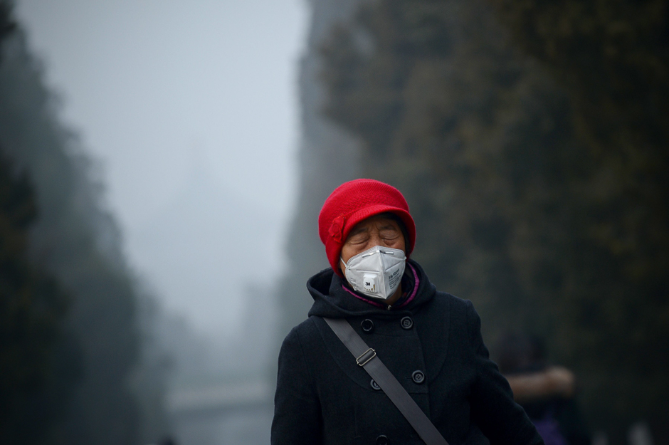 An elderly woman wearing a mask closes her eyes, as she walks at a park in Beijing. Heavy smog suffocated northeast China for a fifth day, with hundreds of flights cancelled and road and rail transport grinding to a halt under the low visibility conditions. PHOTO: AFP