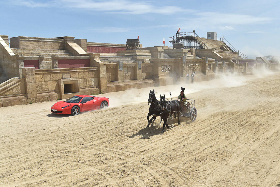 Ferrari driver Fabio Barone and his Ferrari 458 Italia competes against a Roman chariot drawn by two horses on 