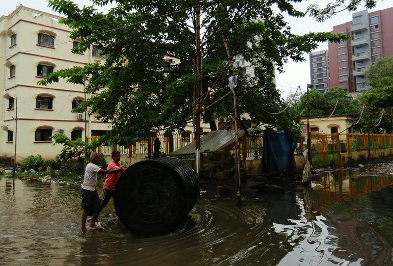 men push a water tank through a partially flooded street at a residential area in mumbai india photo reuters