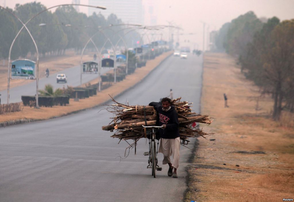 a man pushes a bicycle loaded with tree branches to be used for heating and cooking on a road in islamabad pakistan photo reuters