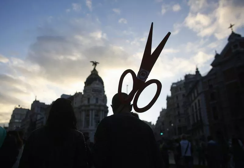 a protester holding a cut out of scissors signifying cuts photo reuters a protester holding a cut out of scissors signifying cuts photo reuters