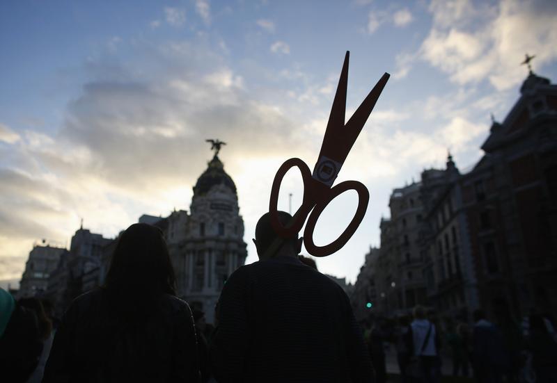 a protester holding a cut out of scissors signifying cuts photo reuters