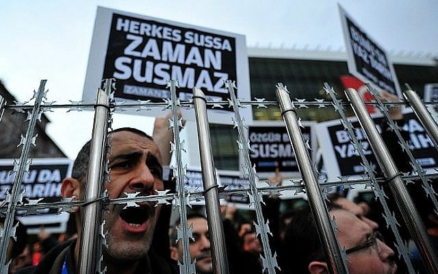 staff members and supporters of zaman newspaper shout slogans and hold placards reading free press can not be silenced during a protest against a raid by counter terror police in istanbul on december 14 2014 photo afp