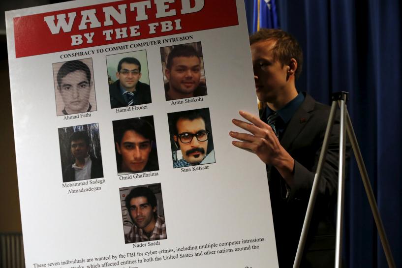 an aide unveils a wanted poster before u s attorney general loretta lynch and federal bureau of investigation director james comey hold a news conference to announce indictments on iranian hackers for a coordinated campaign of cyber attacks in 2012 and 2013 on several u s banks and a new york dam at the justice department in washington photo reuters