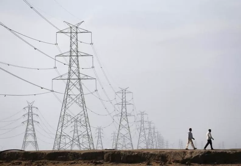 men walk past electric pylons photo reuters