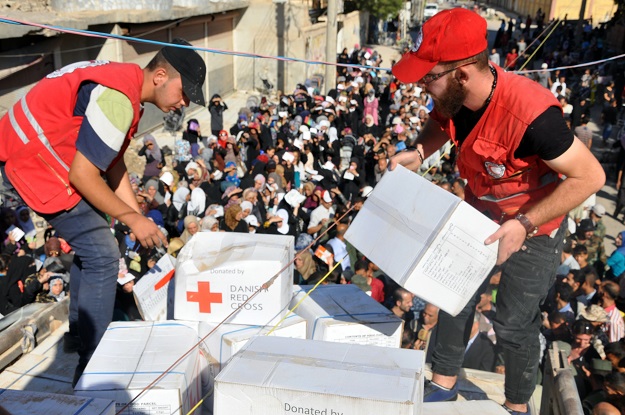 members of the syrian red crescent distribute humanitarian aid parcels to local residents in the northeastern city of deir ezzor photo afp