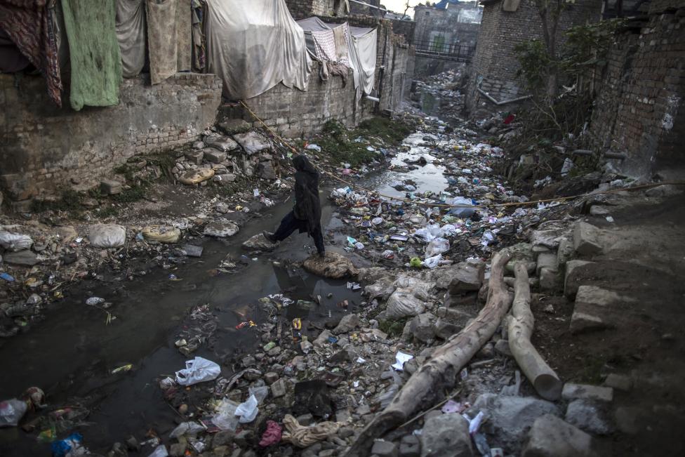 a woman crosses an open sewer as she makes her way to her house in the slum photo reuters