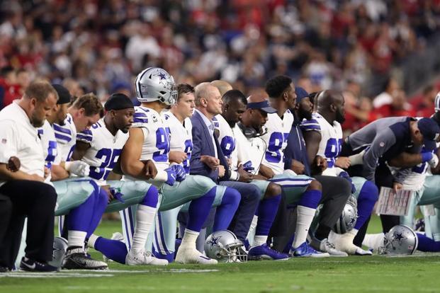 members of the dallas cowboys link arms before the national anthem at the start of the nfl game against the arizona cardinals in glendale photo afp