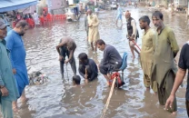 the head sweeper looks prominent sitting on a chair issuing instructions while drain divers try to clear a clogged gutter to allow rainwater to flow out on a street in hyderabad on friday photo express