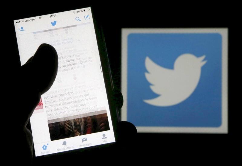 a man reads tweets on his phone in front of a displayed twitter logo in bordeaux southwestern france march 10 2016 photo reuters