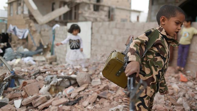 a boy carries a toy machine gun next to destroyed houses during a vigil marking one year since the saudi aggression on a residential area in sana a yemen photo reuters
