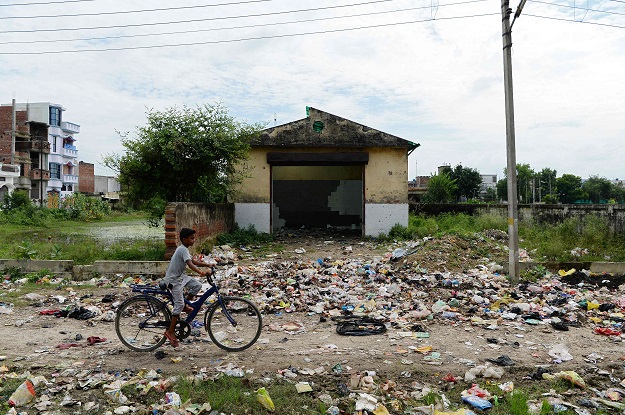 a boy rides a bicycle near a littered path in gonda district in the indian state of uttar pradesh photo afp
