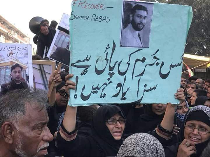 a mother raising the placard in a protest to demand safe recovery of her missing son photo author