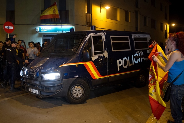 people holding spanish and catalan flags applaud as a police van leaves the hotel mont palau in pineda de mar on october 3 2017 photo afp