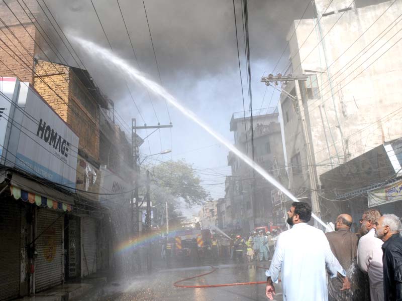 a fireman tries to douse flames in a warehouse at the electronics market on college road photo agha mehroz express